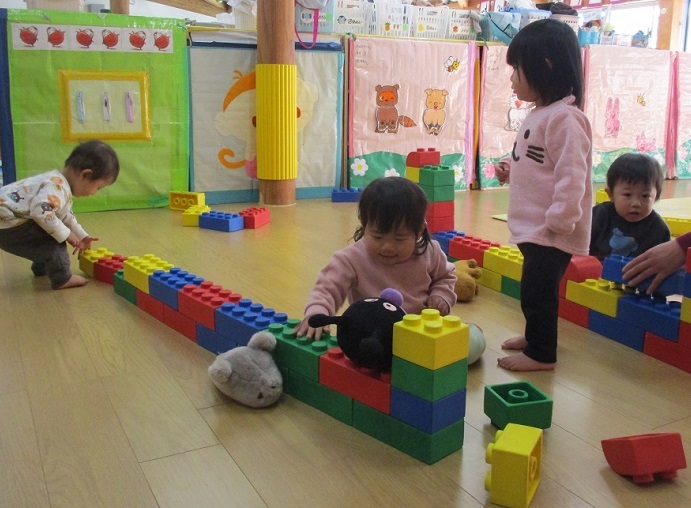 0歳児が大きなソフトブロックをつなげて遊んでいる。