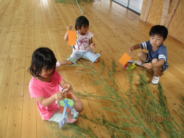 子ども達が笹に七夕飾りをつけています。
