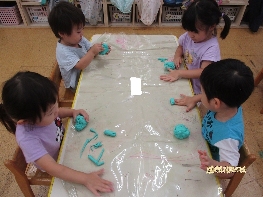 2歳児は粘土遊びをしている。手で粘土を押さえ、上下に動かして伸ばしている。