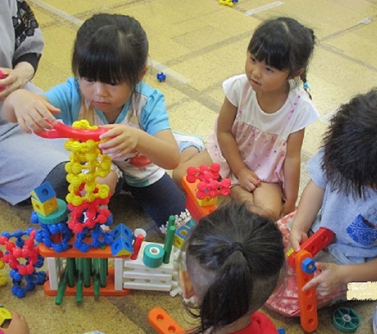 気温が高い日は部屋で遊びます。4歳児がブロックを積み上げている。落ちないようにそっと置こうとしている。