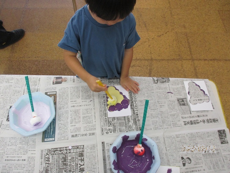 3歳児がたんぽに絵の具を付けてぶどうの型の中を塗っている。