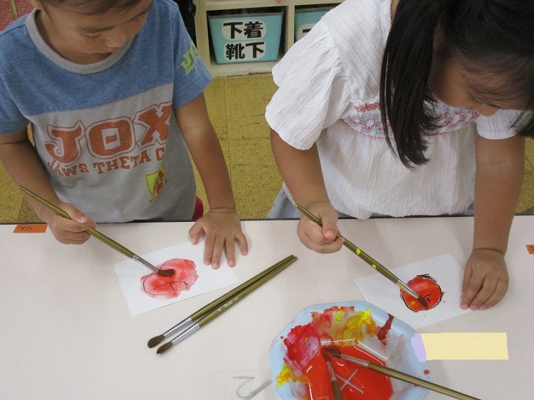 4歳児は絵筆を使って色を付けます。　「りんごは赤だよね。」色づく絵を楽しみながら取り組んでいる。