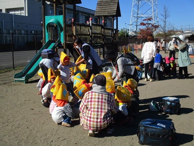 子ども達は園庭に避難し、防災頭巾を被って指示を待っている。