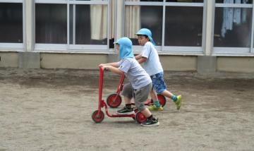 子どもたちがキックボードに乗っている。