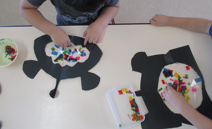 4歳児が作った提灯アンコウに、刻んだパラフィン紙を振りまいている。