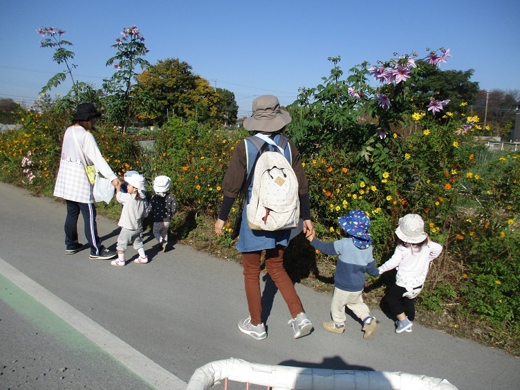 1歳児が手を繋いで道路を歩いている。