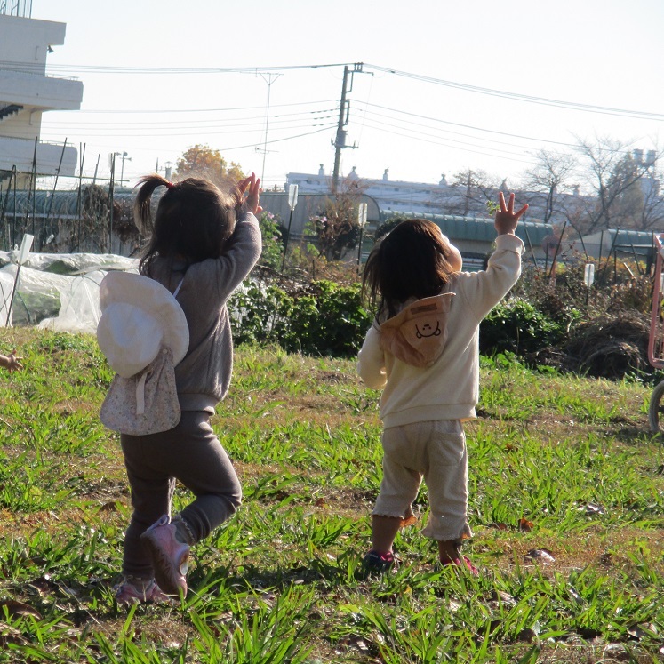 子どもたちが空を飛ぶ飛行機を見つけ、手を振っている。
