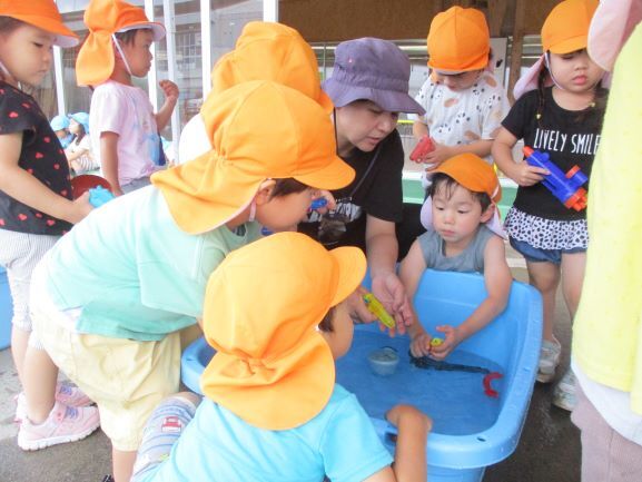 子どもたちが水を溜めたタライの周りに集まっている。