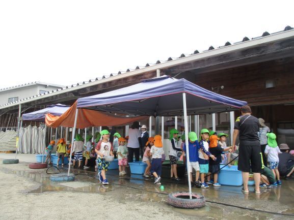たくさんの子どもたちがテントの下で水遊びをしている