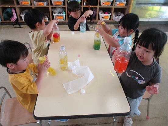 子どもたちが水の入ったペットボトルにお花紙を入れている。