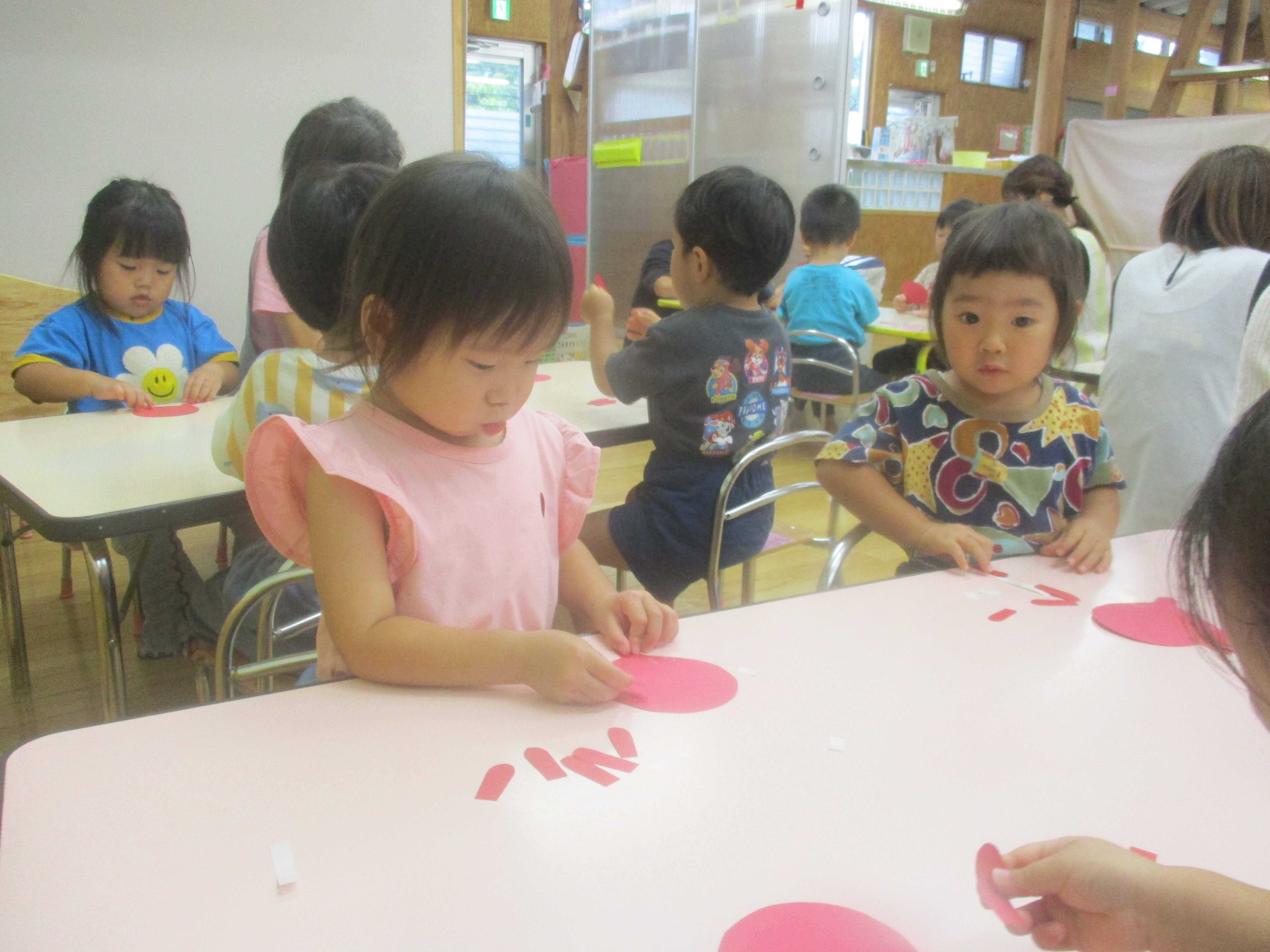 子どもが並んで座り、色画用紙のタコの足を貼り付けている。