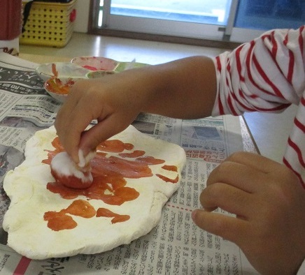 4歳児クラスが紙粘土で作ったナンに色付けをしている。
