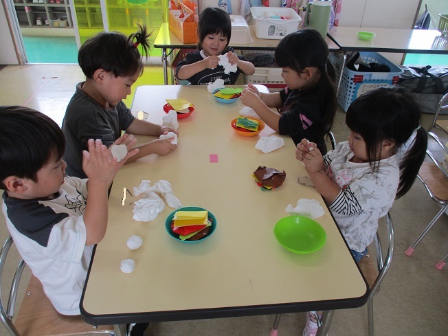 3歳児が紙粘土でハンバーガーのバンズを作っている。